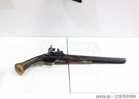 Decorated antique weapon with intricate wood pattern. A vintage 19th century pistol on display at the museum Decorated antique weapon with intricate wood pattern. A vintage 19th century pistol on display at the museum 119763099