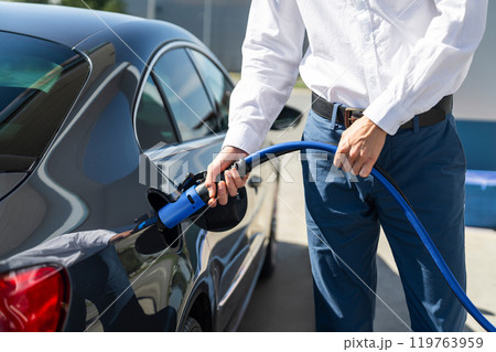 Man holds a hydrogen fueling nozzle on a hydrogen filling station. Refueling car with hydrogen fuel 119763959