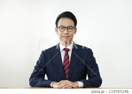 カメラ目線で微笑むメガネをかけた30代後半のビジネスマン カメラ目線で微笑むメガネをかけた30代後半のビジネスマン 119765246