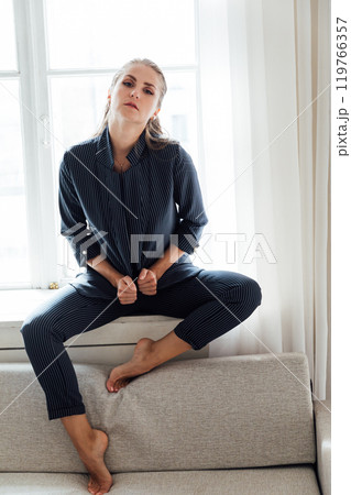 Beautiful fashionable woman in gray suit sitting by the window 119766357