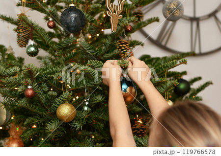 A child decorates a tree for the Christmas. 119766578