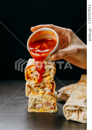 Delicious chicken wraps with vibrant sauce pouring for a perfect snack or meal presentation 119767051