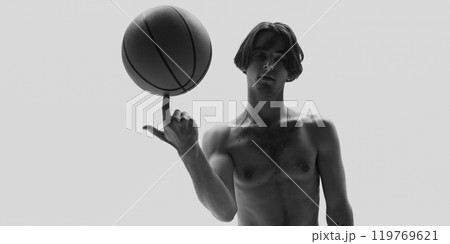 Dynamic photo in monochrome filter. Man spins basketball on his finger showcasing dexterity and control. 119769621