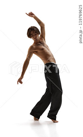 Man strikes graceful pose, balanced on one foot with his arm raised, showing blend of strength and elegance against white background. 119769625