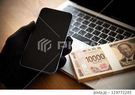 お金を盗む犯罪者の手とスマホとパソコン お金を盗む犯罪者の手とスマホとパソコン 119772285