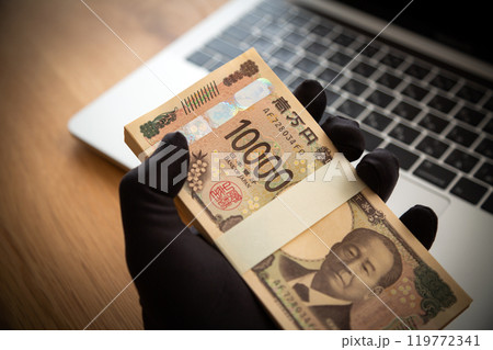 お金を盗む犯罪者の手とパソコン 119772341