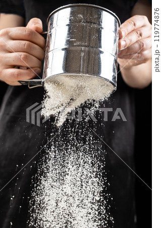 The cook sifts the wheat flour through a metal sieve The cook sifts the wheat flour through a metal sieve 119774876