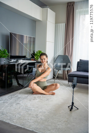 Young woman doing yoga using a sports app on her mobile phone at home. Online training concept 119775576