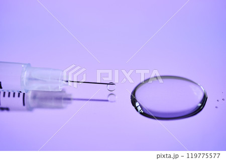 Injection syringe on a medical tray in bright violet color. 119775577