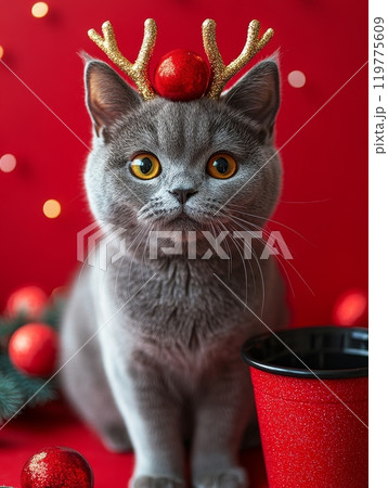 A cheerful and festive cat wearing cute reindeer antlers amidst colorful holiday decorations for Christmas 119775609