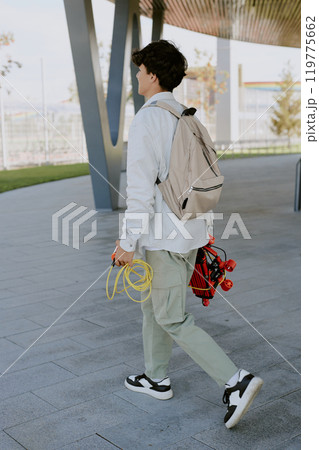 Unrecognizable teen boy with beige backpack and red robot with yellow wires in hands walking 119775662