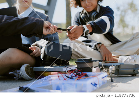 Medium closeup shot of unrecognizable kids crafting drone together in park under open sky Medium closeup shot of unrecognizable kids crafting drone together in park under open sky 119775736
