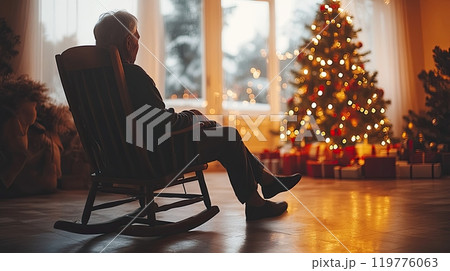 an elderly person, alone in welcoming house on Christmas, sitting in a rocking chair by the tree  119776063