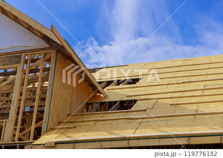 Plywood is installed on wooden roofing trusses at assembled roof of house in construction 119776182