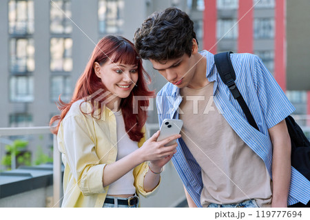 Friends young guy and girl college students talking looking at smartphone together, outdoor Friends young guy and girl college students talking looking at smartphone together, outdoor 119777694