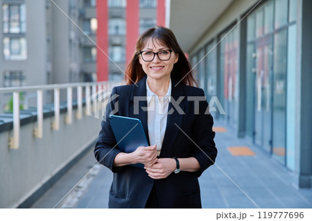 Mature confident business woman with digital tablet in black suit outdoors Mature confident business woman with digital tablet in black suit outdoors 119777696