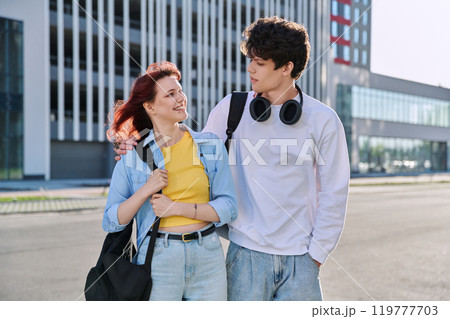 Teenage college students guy and girl talking, standing outdoor, urban style 119777703