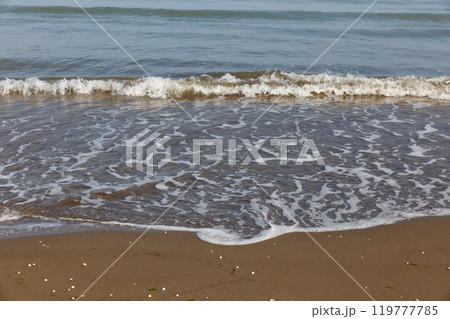 Beach with waves and white foam on the sand and sea background. Caspian Sea 119777785