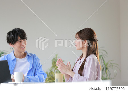 アイデアを話す女性と「実現性が低い」と感じているクリエイター男性_1 119777803