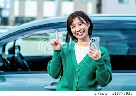 車の前でスマートフォンを持った笑顔の女性 スマホと車 車の前でスマートフォンを持った笑顔の女性 スマホと車 119777936