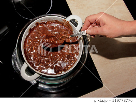 Powdered sugar, cocoa butter and grated cocoa in a container for making chocolate are heated in a water bath. Powdered sugar, cocoa butter and grated cocoa in a container for making chocolate are heated in a water bath. 119778770