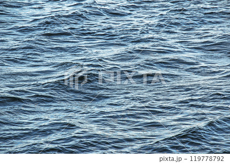 The background of the surface of the water of the river with small ripples and reflections of autumn colors. The background of the surface of the water of the river with small ripples and reflections of autumn colors. 119778792
