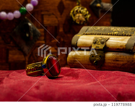 reproduction golden ring with ruby gem decorated medieval with an ivory casket on a red velvet table 119778988