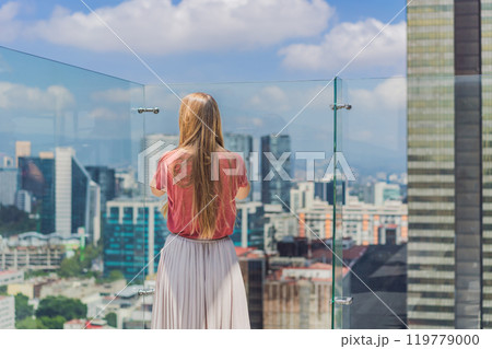 Female tourist or businesswoman standing on a skyscraper rooftop with a panoramic view of Mexico City. Travel or international business in Mexico concept Female tourist or businesswoman standing on a skyscraper rooftop with a panoramic view of Mexico City. Travel or international business in Mexico concept 119779000