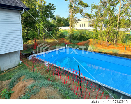 Installation of swimming pool construction at ground near house in back yard 119780343