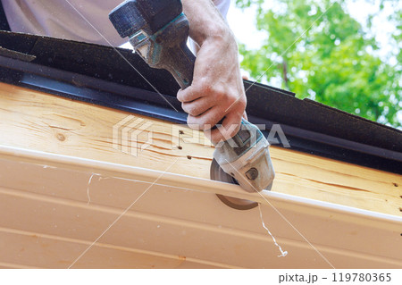Cutting off established vinyl soffit panels facade ceiling of new house to a given size Cutting off established vinyl soffit panels facade ceiling of new house to a given size 119780365