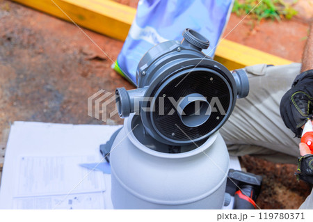 Worker installing sand filter system tank equipment for cleaning swimming pools Worker installing sand filter system tank equipment for cleaning swimming pools 119780371