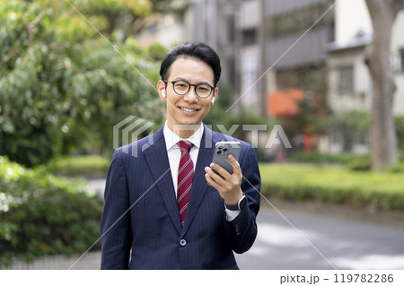 スマートフォンを持ったイヤホンをした30代後半のビジネスマン カメラ目線 スマートフォンを持ったイヤホンをした30代後半のビジネスマン カメラ目線 119782286