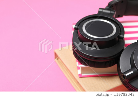 Books with modern headphones, on a pink background. Books with modern headphones, on a pink background. 119782345