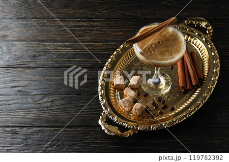 Martini espresso cocktail, cinnamon and sugar on golden tray on wooden background, space for text Martini espresso cocktail, cinnamon and sugar on golden tray on wooden background, space for text 119782392