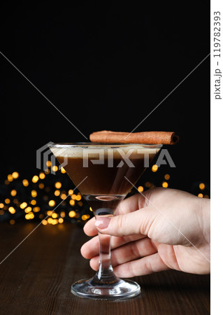 Martini espresso cocktail in glass and female hand on wooden table on black background Martini espresso cocktail in glass and female hand on wooden table on black background 119782393