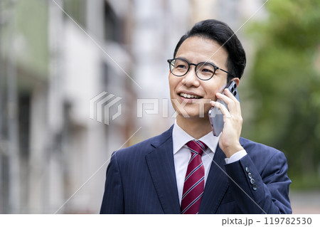 スマートフォンで通話をする30代後半のビジネスマン スマートフォンで通話をする30代後半のビジネスマン 119782530