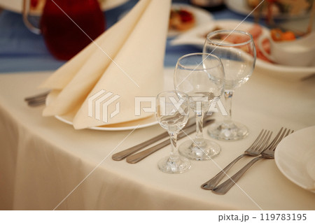 A table with a white tablecloth and a napkin folded in a triangle. Wedding table setting. A table with a white tablecloth and a napkin folded in a triangle. Wedding table setting. 119783195