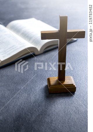 Religion cross and opened book of Holy Bible. It is laying on table. Symbol of faith and worship in God Religion cross and opened book of Holy Bible. It is laying on table. Symbol of faith and worship in God 119783482