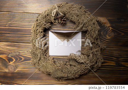 Top view of envelope and postcard with brown card with words Thank You written on it and wreath Top view of envelope and postcard with brown card with words Thank You written on it and wreath 119783554