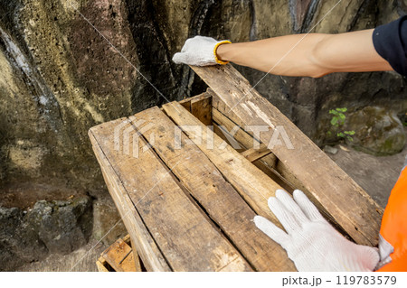 Workers in safety vest and glove disassembling pallet parts 119783579