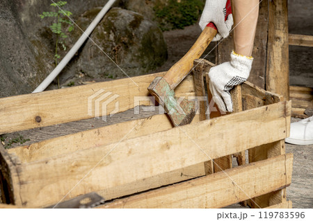 Workers in safety vest and glove using axe to work disassembling pallet parts Workers in safety vest and glove using axe to work disassembling pallet parts 119783596