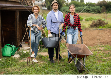 Portrait of three farmers with wheelbarrow of dry tops in farmer field Portrait of three farmers with wheelbarrow of dry tops in farmer field 119783947