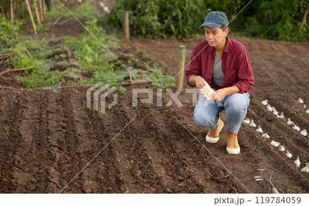 Young woman planting seeds in field Young woman planting seeds in field 119784059