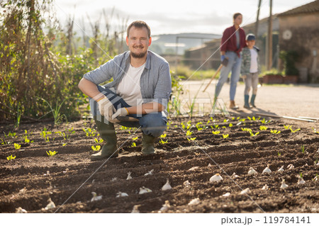 Young man planting seeds in field Young man planting seeds in field 119784141