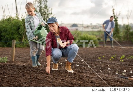 Woman planting seeds boy watering beds Woman planting seeds boy watering beds 119784370