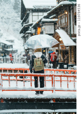 Woman tourist Visiting Ginzan Onsen in Yamagata, happy Traveler sightseeing Japanese Onsen village with Snow in winter season. landmark and popular for attraction in Japan. Travel and Vacation concept 119784536