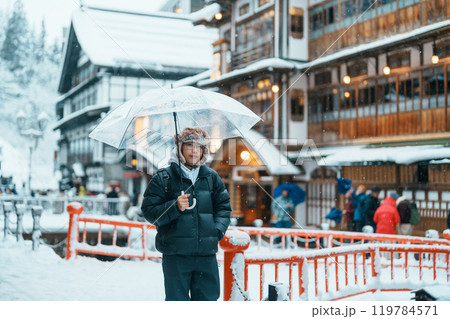 man tourist Visiting Ginzan Onsen in Yamagata, happy Traveler sightseeing Japanese Onsen village with Snow in winter season. landmark and popular for attraction in Japan. Travel and Vacation concept 119784571