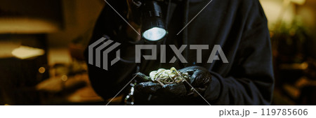 Website banner of unrecognizable thief with black gloves holding golden jewelry under flashlight 119785606