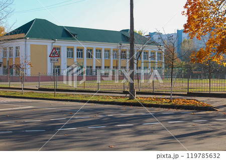 A two-story school building in the fall. Sports ground on the school grounds.  119785632
