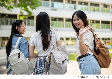 A happy Asian female college student is on the way to class with her friends. A happy Asian female college student is on the way to class with her friends. 119785793